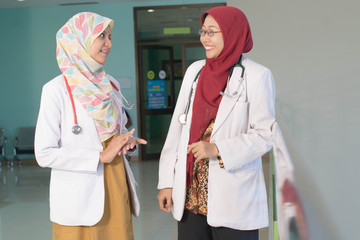 two female asian hijab doctor's discuss and studying about patient's document on the loby hall