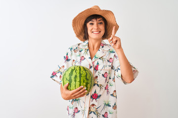 Woman on vacation wearing summer hat holding watermelon over isolated white background surprised with an idea or question pointing finger with happy face, number one