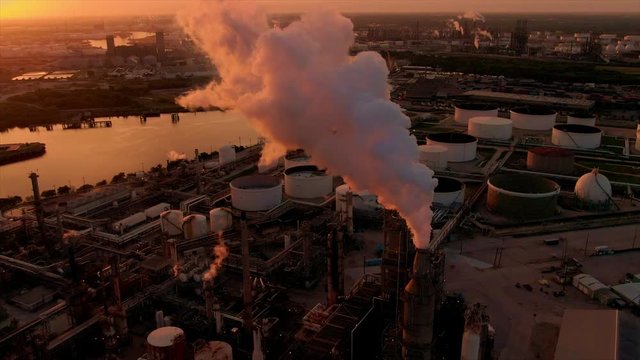 Flying over a refinery smoke tower at sunrise