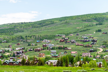 Fototapeta na wymiar Mount Crested Butte village in summer with colorful grass and wooden lodging houses on hills with green lush color