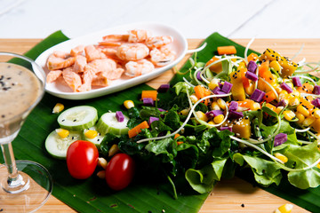 Fresh salad plate with shrimp, salmon, tomato and mixed greens  on wooden background .