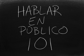 The words Hablar En Público 101 on a blackboard in chalk.  Translation: Public Speaking 101