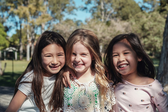 Happy and healthy multiethnic young little girls hugging and smiling in the park, best friends and friendship,all lives matter, no to racism, equality concept