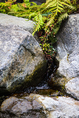 Naklejka na ściany i meble granite rocks with water trickling down the rock face to small pool