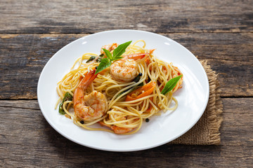 Spaghetti with spicy fried shrimp on a wooden table