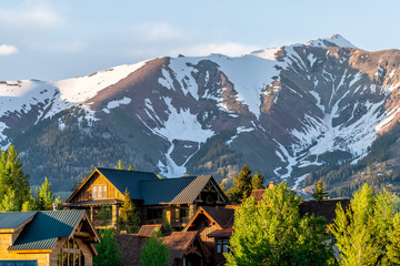 Mount Crested Butte Colorado village houses in summer with colorful sunset on green trees and...