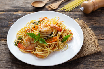 Spaghetti with spicy fried shrimp on a wooden table