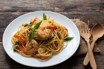 Spaghetti with spicy fried shrimp on a wooden table