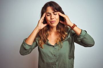 Young beautiful woman wearing green shirt standing over grey isolated background with hand on headache because stress. Suffering migraine.