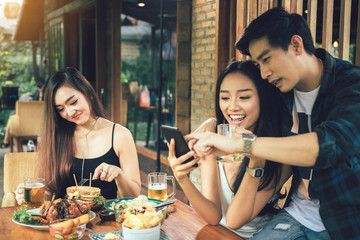 Asian single woman envious with love couple doing take selfie at restaurant.