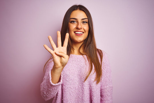 Young beautiful woman wearing casual sweater standing over isolated pink background showing and pointing up with fingers number four while smiling confident and happy.