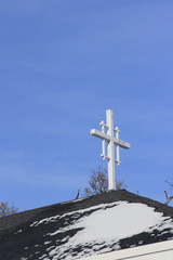 White crosss with a blue sky background on top of a steeple.