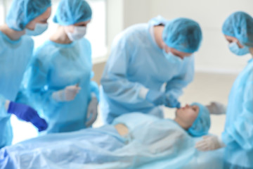 Plastic surgeons operating patient in clinic, blurred view