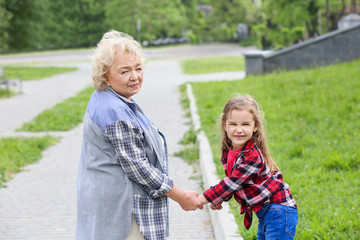 Cute little girl with grandmother walking in park