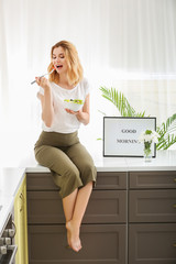 Fototapeta na wymiar Woman eating healthy vegetable salad in kitchen