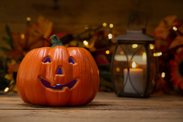 Fototapeta premium Halloween pumpkin head jack lantern on a wooden background with blurry lights, background for the holiday