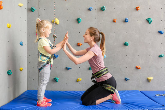 Little girl and instructor giving each other high-five in climbing gym