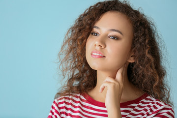 African-American woman checking her pulse on color background