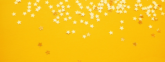 Golden stars glitter on yellow paper background