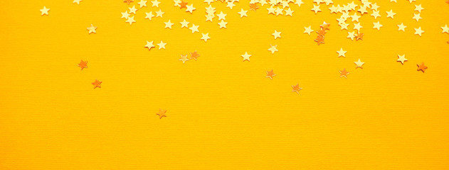 Golden stars glitter on yellow paper background