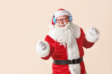 Portrait of Santa Claus listening to music on light background