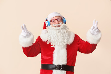 Portrait of Santa Claus listening to music on light background