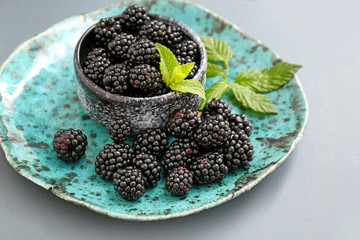 Fototapeta na wymiar Plate with blackberry on grey background