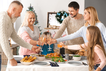 Happy family clinking glasses during Christmas dinner at home