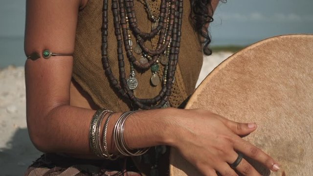 Isolated view of woman hands playing on ethnic drum instrument on the beach in slow motion