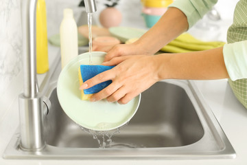 Woman washing dishes in kitchen sink