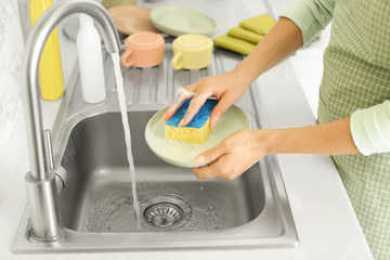 Woman washing dishes in kitchen sink