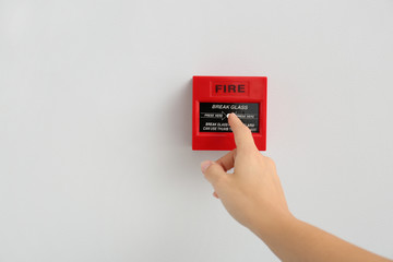 Woman using manual call point of fire alarm system