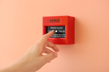 Woman using manual call point of fire alarm system