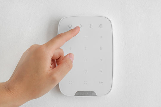Woman entering code on panel of modern security system