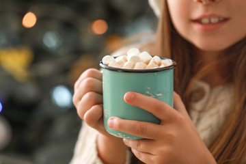 Little girl drinking hot chocolate at home on Christmas eve, closeup