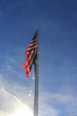 Red, White & Blue, U.S. flag, flying in the blue sky with white clouds, on a flag pole.