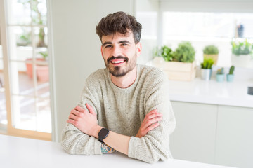 Handsome young man smiling cheerful at the camera with crossed arms and a big smile on face showing teeth