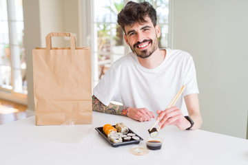 Young man eating sushi asian food and noodles using choopsticks from take away delivery
