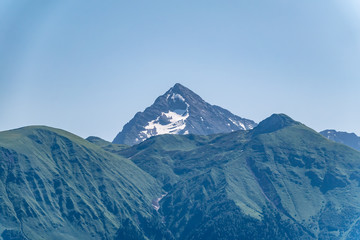 Naklejka na ściany i meble High mountains with green slopes and snowy peaks.