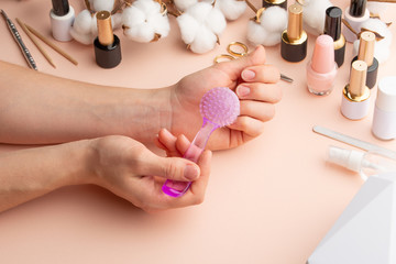 Nail care. Beautiful women hands making nails painted by pink delicate nail polish on a gentle background. Female hands near a set of professional manicure tools. Beauty care. Closeup manicure.