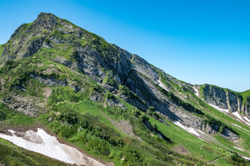 Fototapeta na wymiar Mountain range with rocks and trees against a clear blue sky.