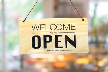 A business sign that says open on cafe or restaurant hang on door at entrance.