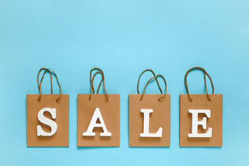 Text SALE from white volume letters and blank shopping bags on blue background. Top view Flat lay Mockup Concept discount. Creative template for your text, design, ad or advertisement