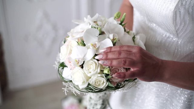 The bride is holding a beautiful bouquet of white roses and orchids