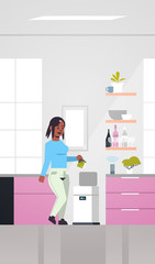 african american woman putting trash in electronic recycling bin controlled by smart speaker voice recognition activated digital assistant concept modern kitchen interior vertical full length