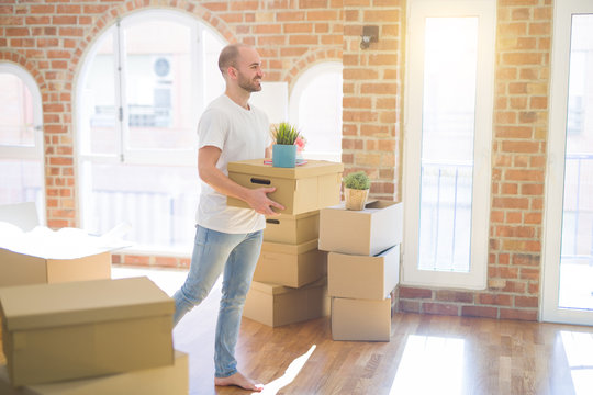 Young handsome man moving to a new house, holding cardboxes smiling very happy for new apartment