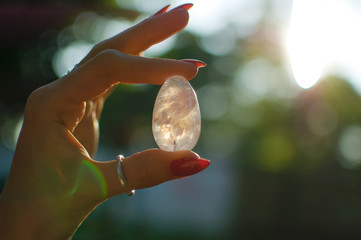 Close up photo of female hand with transparent amethyst yoni egg for vumbuilding. Quartz crystal...