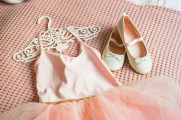 Little shoes and pink dress on a bed in kid bedroom. kid prepare to party. 