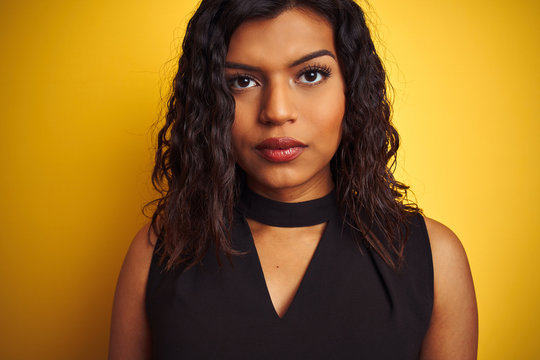 Transsexual transgender woman wearing black t-shirt over isolated yellow background with a confident expression on smart face thinking serious