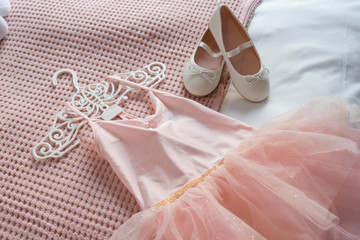 Little shoes and pink dress on a bed in kid bedroom. kid prepare to party. 